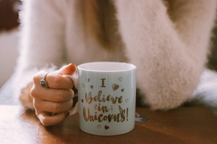 Hand hält eine Tasse mit Einhornmotiv