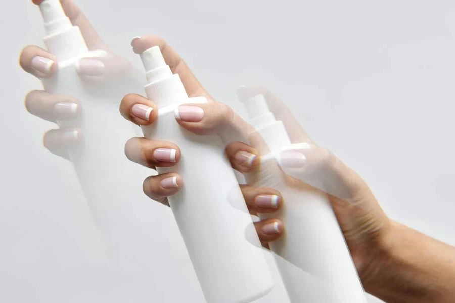 Hands of a person holding white spray bottles