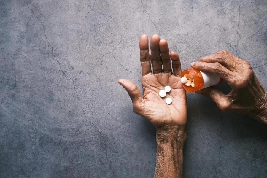 Manos de una persona mayor tomando medicamentos.