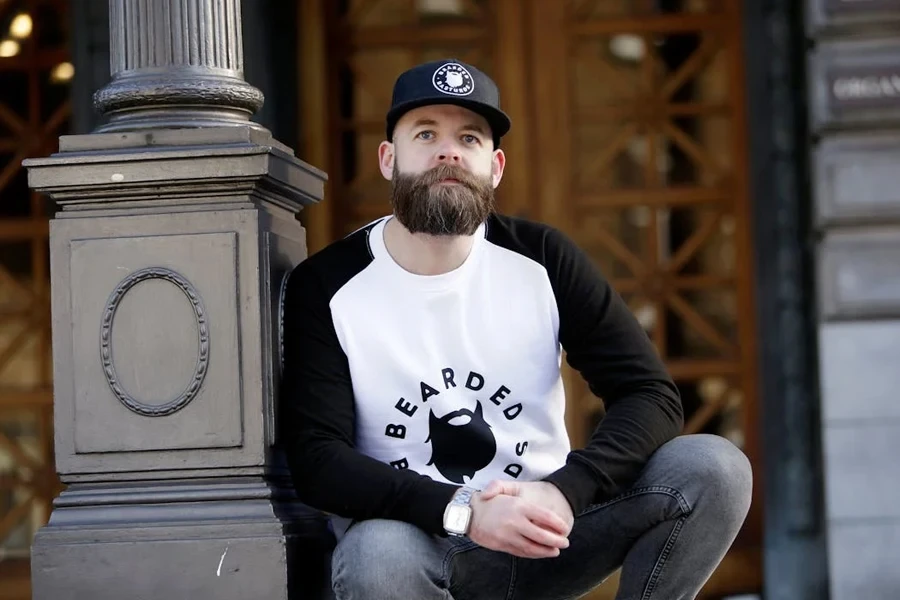 Man leaning on a post in black five-panel hat