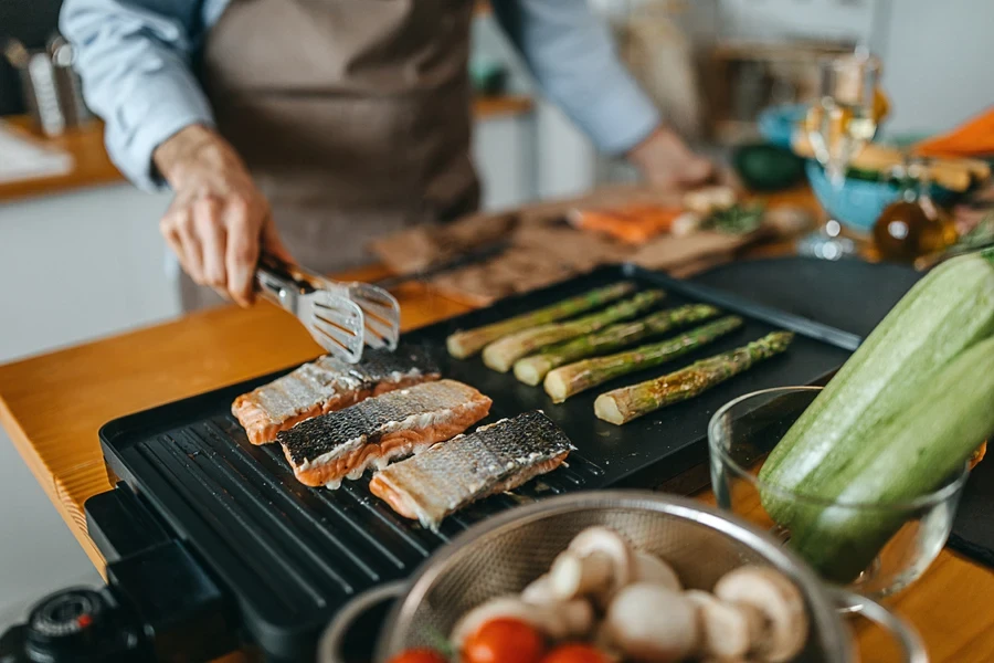 Man roasting salmon steaks on an electric grill