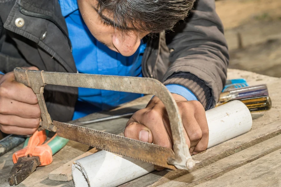 Person cutting PVC pipe with a saw