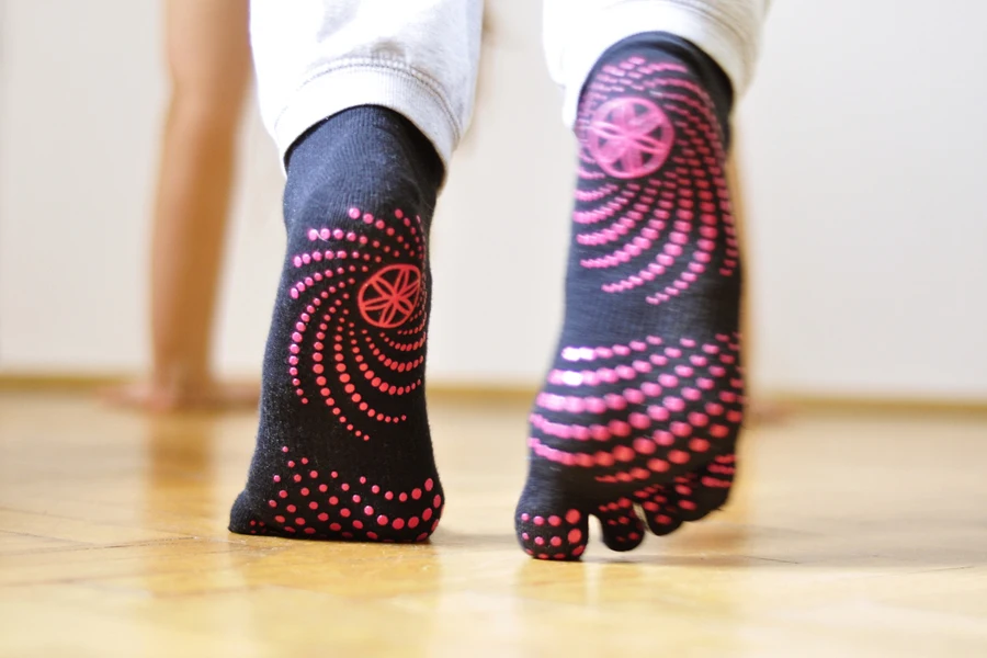 Person wearing black grip socks at home with dark pink grips