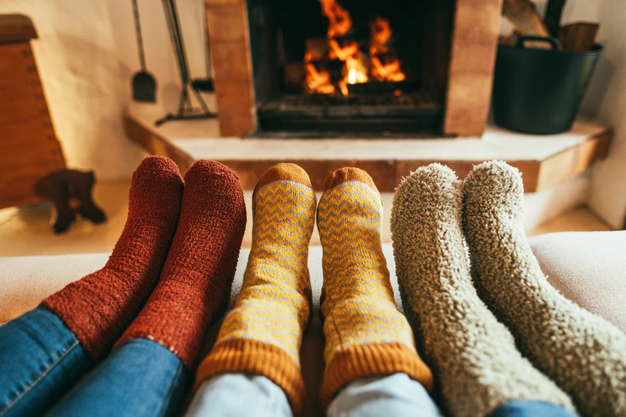 Tre persone con caldi calzini invernali davanti al camino