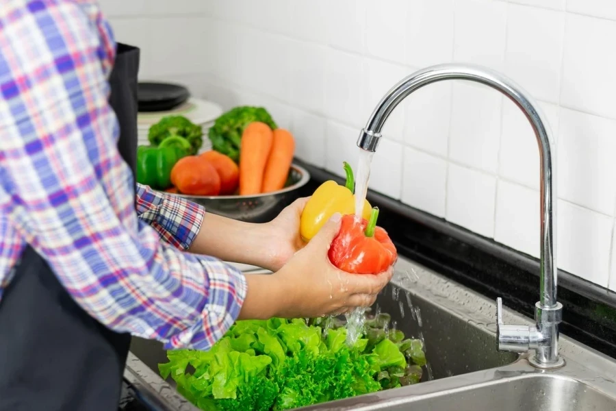 Lavando vegetais na pia da cozinha