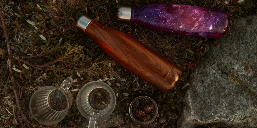 Water Bottles on Brown Grass Beside Glass Cups