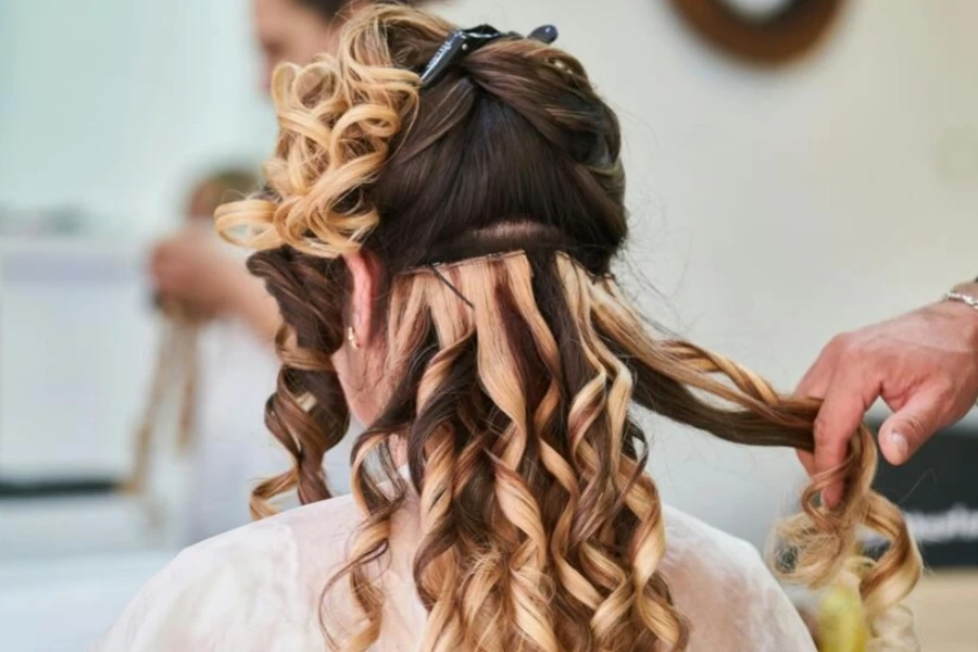 Mujer agregando extensiones de cabello a su cabello.