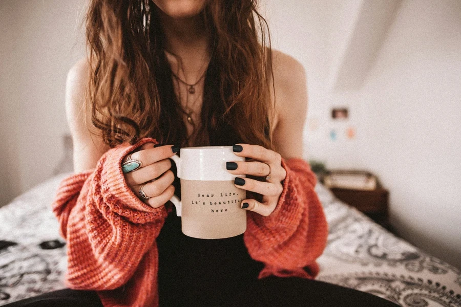 Femme tenant une tasse montrant des couleurs d'ongles d'automne