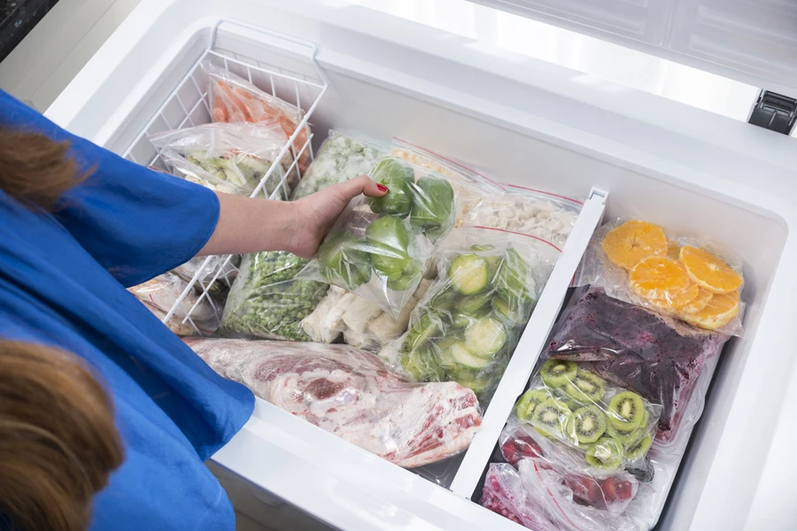 Woman putting pepper in an organized freezer