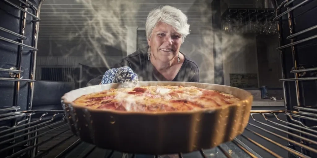 Mujer sacando un plato caliente del horno.