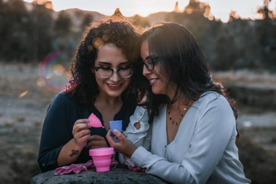 Mulheres olhando para os copos menstruais que estão segurando