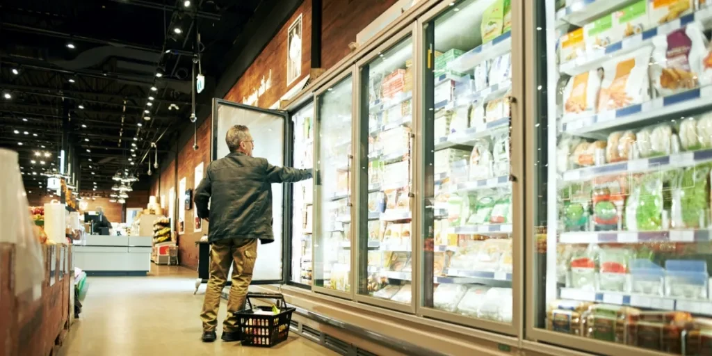 une personne mettant des aliments congelés dans un congélateur commercial