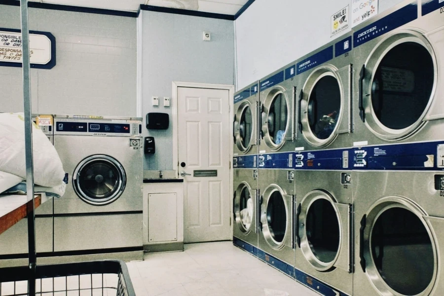 a row of commercial washers and dryers in the laundry room