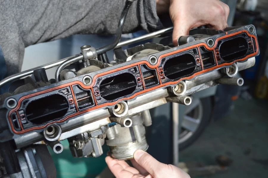 car mechanic holding an intake manifold