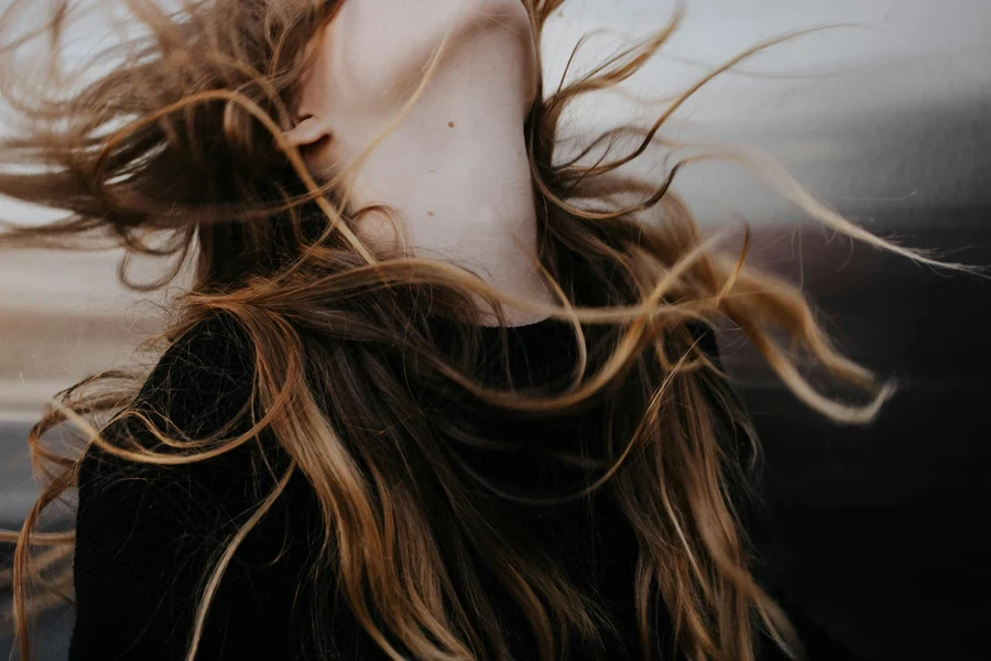 Mujer de cabello naranja con top negro girando la cabeza hacia atrás