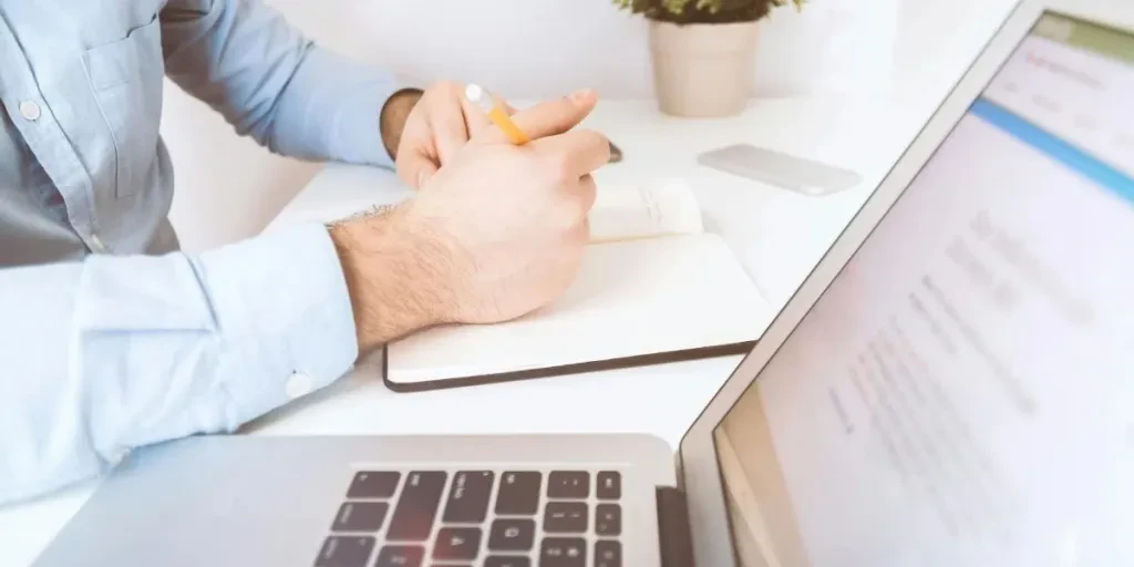 Person holding a pencil and working on a laptop