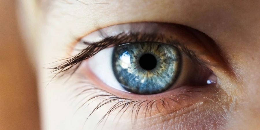 Person öffnet ihr rechtes Auge mit blauer Iris