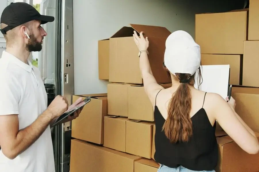 two people checking stacked cardboard boxes