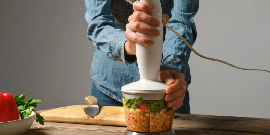 woman preparing salsa or guacamole in blender