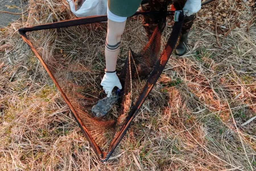 Un hombre sacando basura de una red de pesca