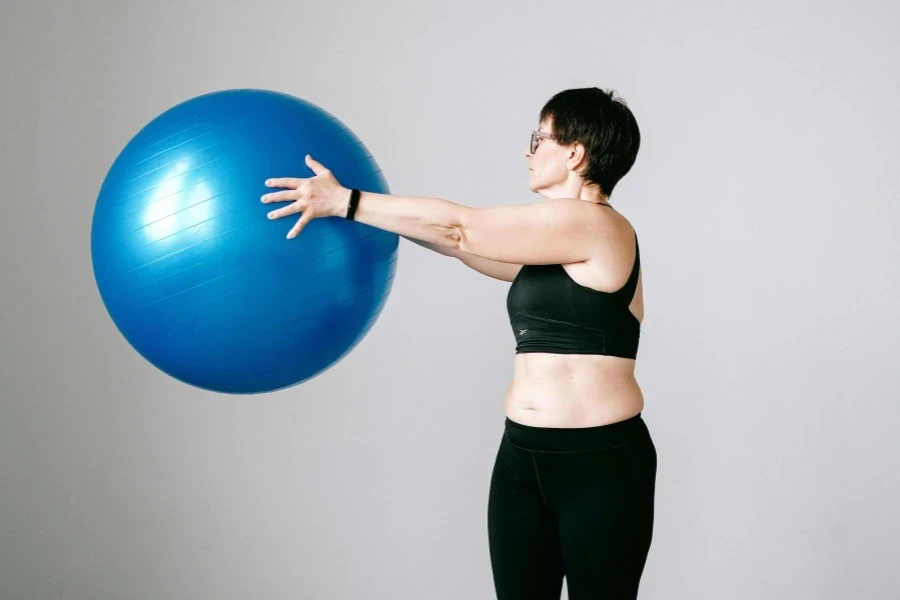 A Woman in Black Sports Bra and Leggings Holding a Blue Exercise Ball