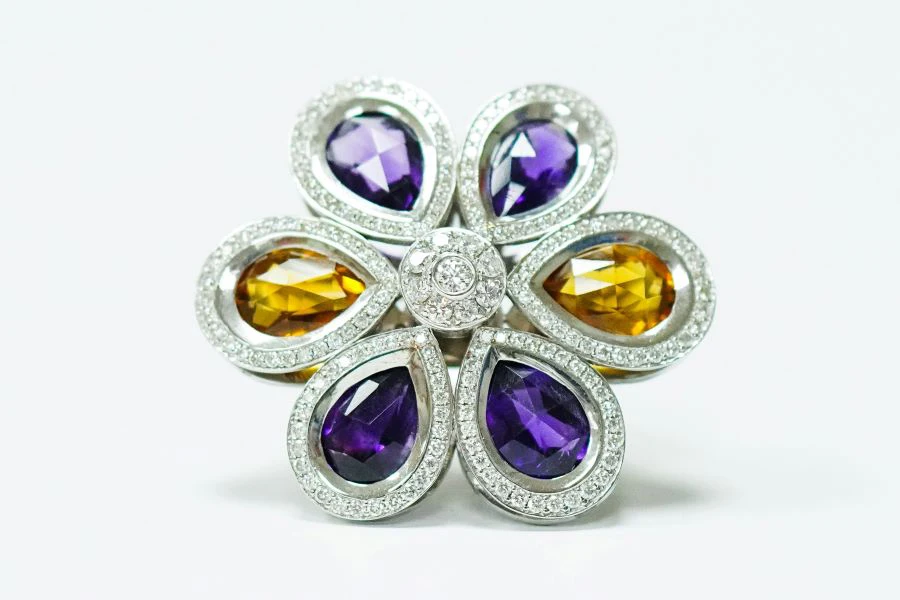 A silver ring with purple and gold gemstones