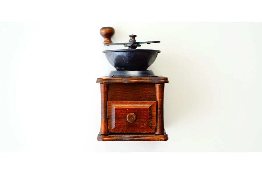 A vintage manual grinder with handle and wooden base