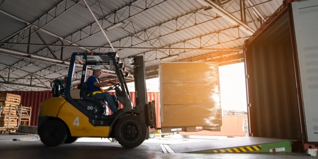 Seorang pekerja gudang sedang mengemudikan forklift