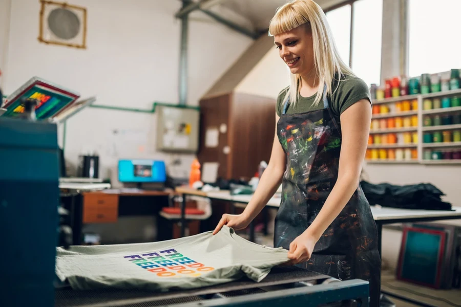 Een arbeider die kleurrijke tekst op een T-shirt drukt