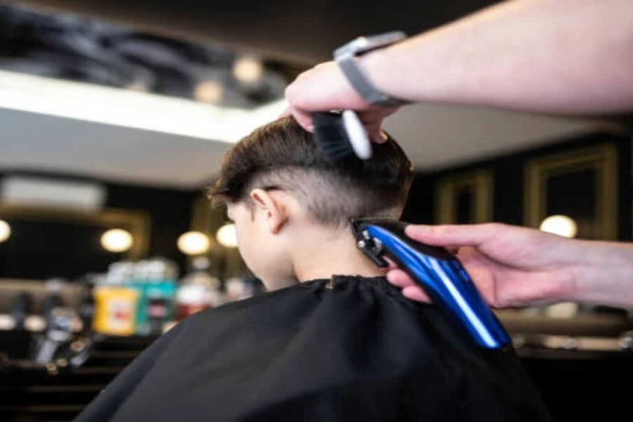 Barber using trimmers on young customer to create burst fade