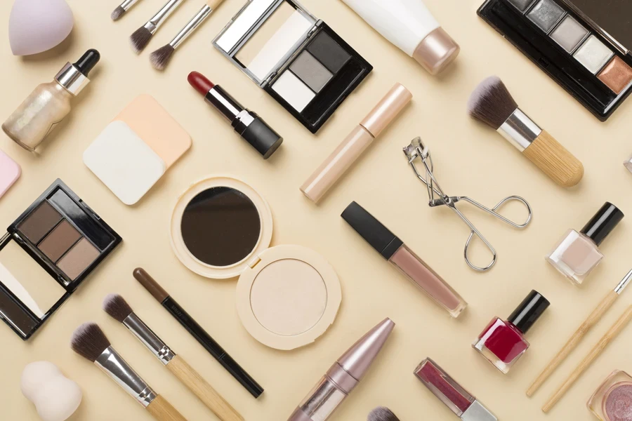 Different makeup products and tools on cream background