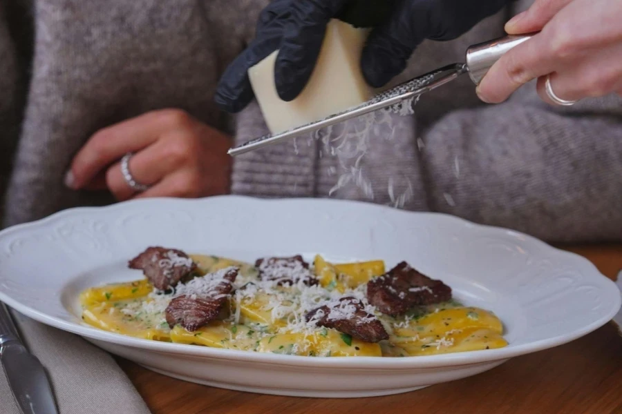 Manos sosteniendo rallador y queso sobre un plato