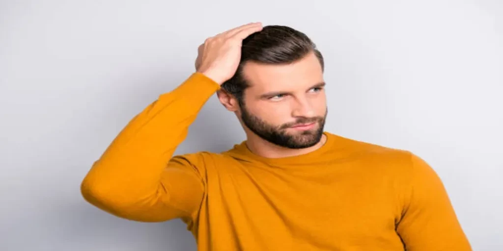 Man in mustard sweater with dark slicked-back hair