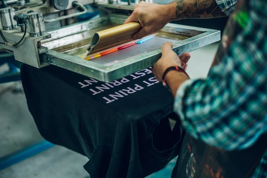 Man zeefdrukt kleuren op een t-shirt