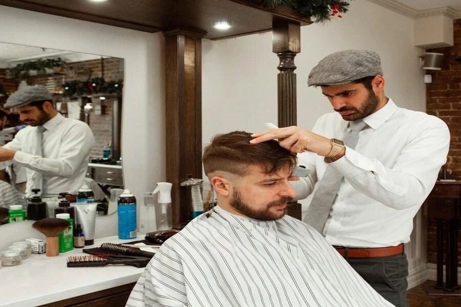 Un homme assis chez le coiffeur pendant qu'il se fait coiffer