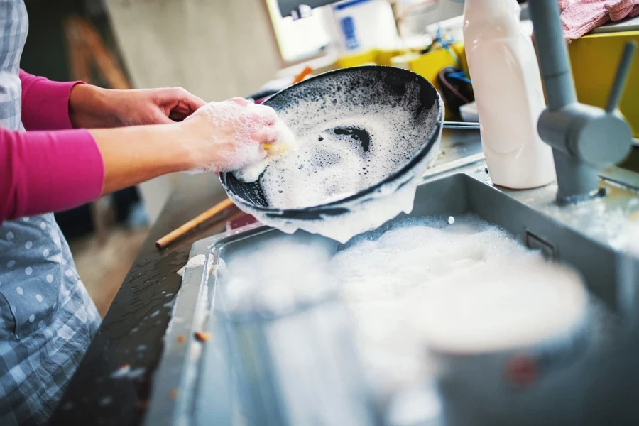 Person washing a skillet in the sink