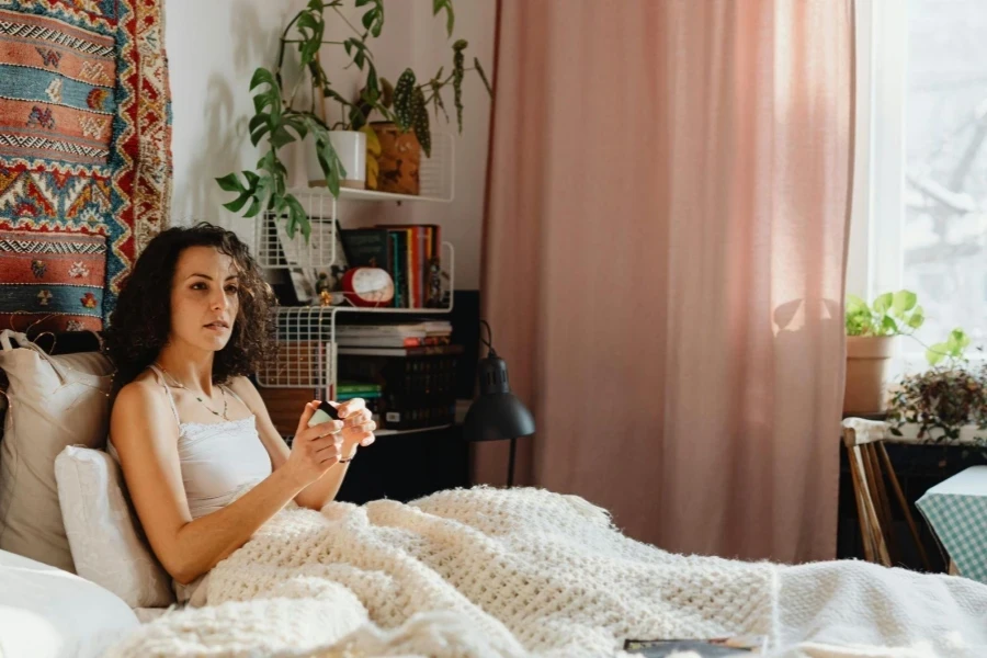 Mujer relajándose bajo una manta en la cama