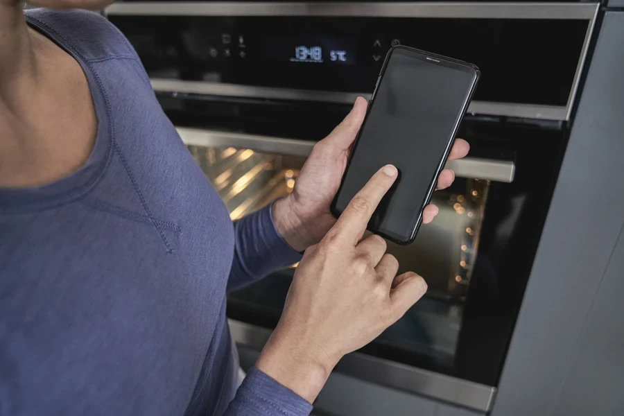 Woman controlling AI oven with her phone