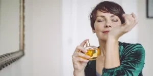 Mujer disfrutando del aroma de su perfume.