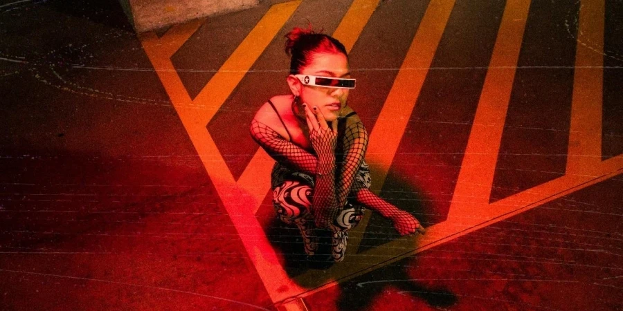 Woman with Fishnet Sleeves Crouching in Red Light