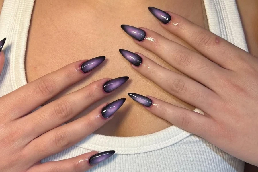 Woman with dark purple aura nails with glossy finish