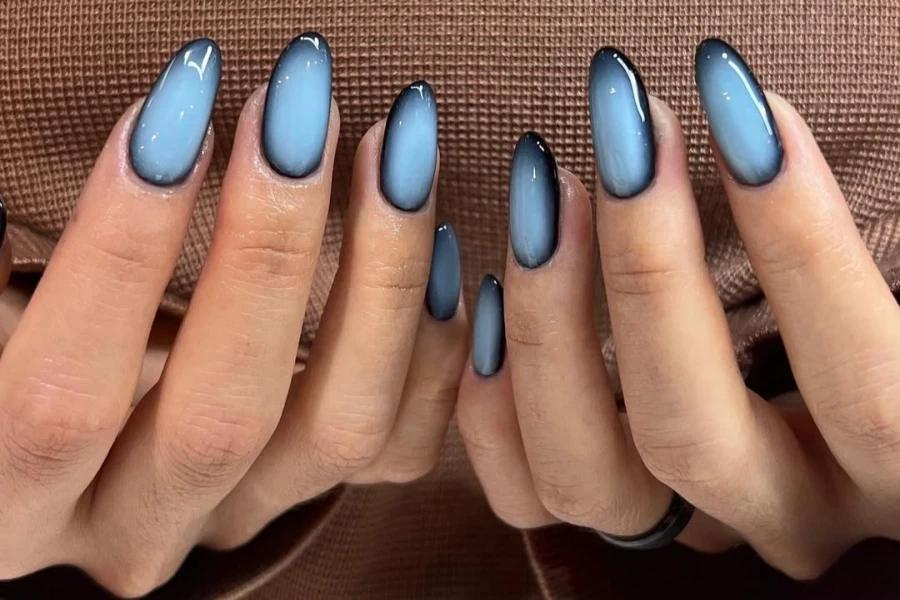 Femme avec des ongles aura multicolores en bleu bébé et noir