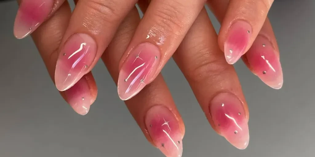 Femme aux ongles roses décorés de petits bijoux