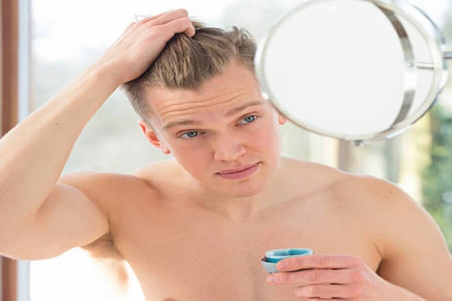 Young man with blond hair adding gel to hair