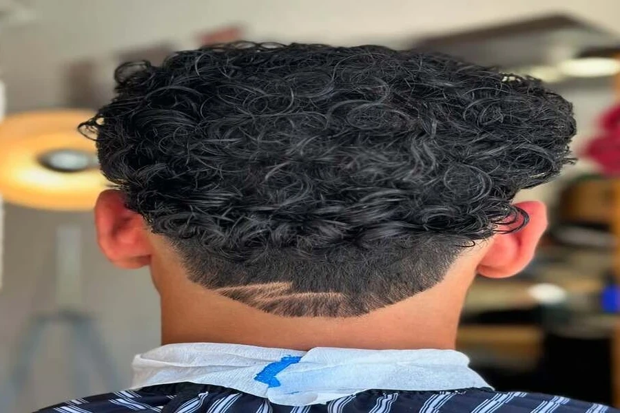 Lelaki muda dengan potongan rambut pudar kerinting segar