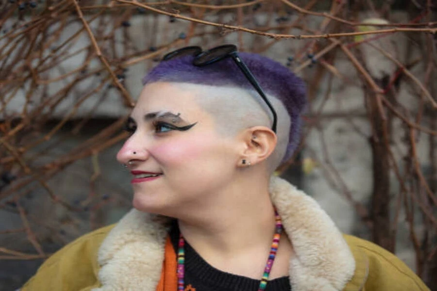 Jeune femme avec une coupe de cheveux dégradée mohawk violette