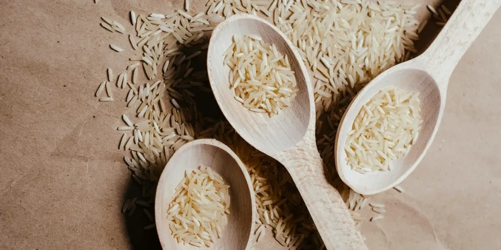 polished white rice grains on wooden spoons