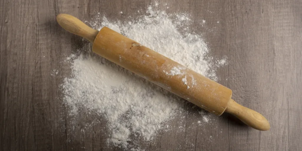 A wooden rolling pin on some flour