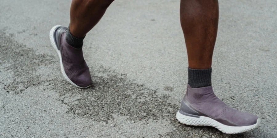 Dynamic close-up of a runner's legs and athletic footwear in motion on a paved road