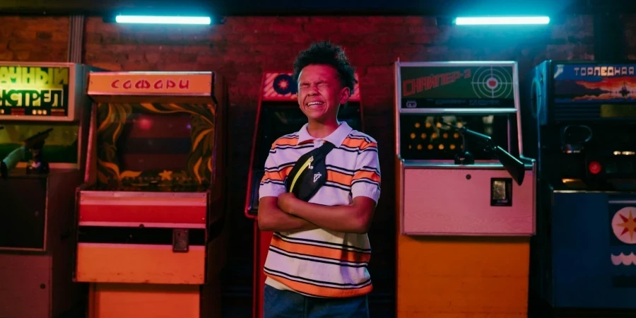 Adolescente sonriente disfrutando de un momento divertido en una vibrante sala de juegos iluminada con neón y máquinas de juegos clásicas.
